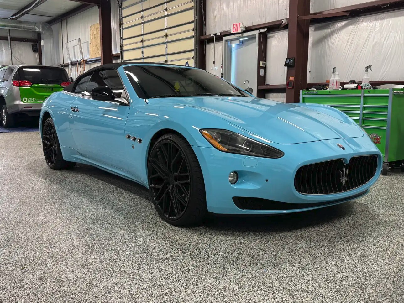 2010 Maserati GranTurismo Convertible wrapped in hi-gloss sky blue, front three-quarter view in the shop